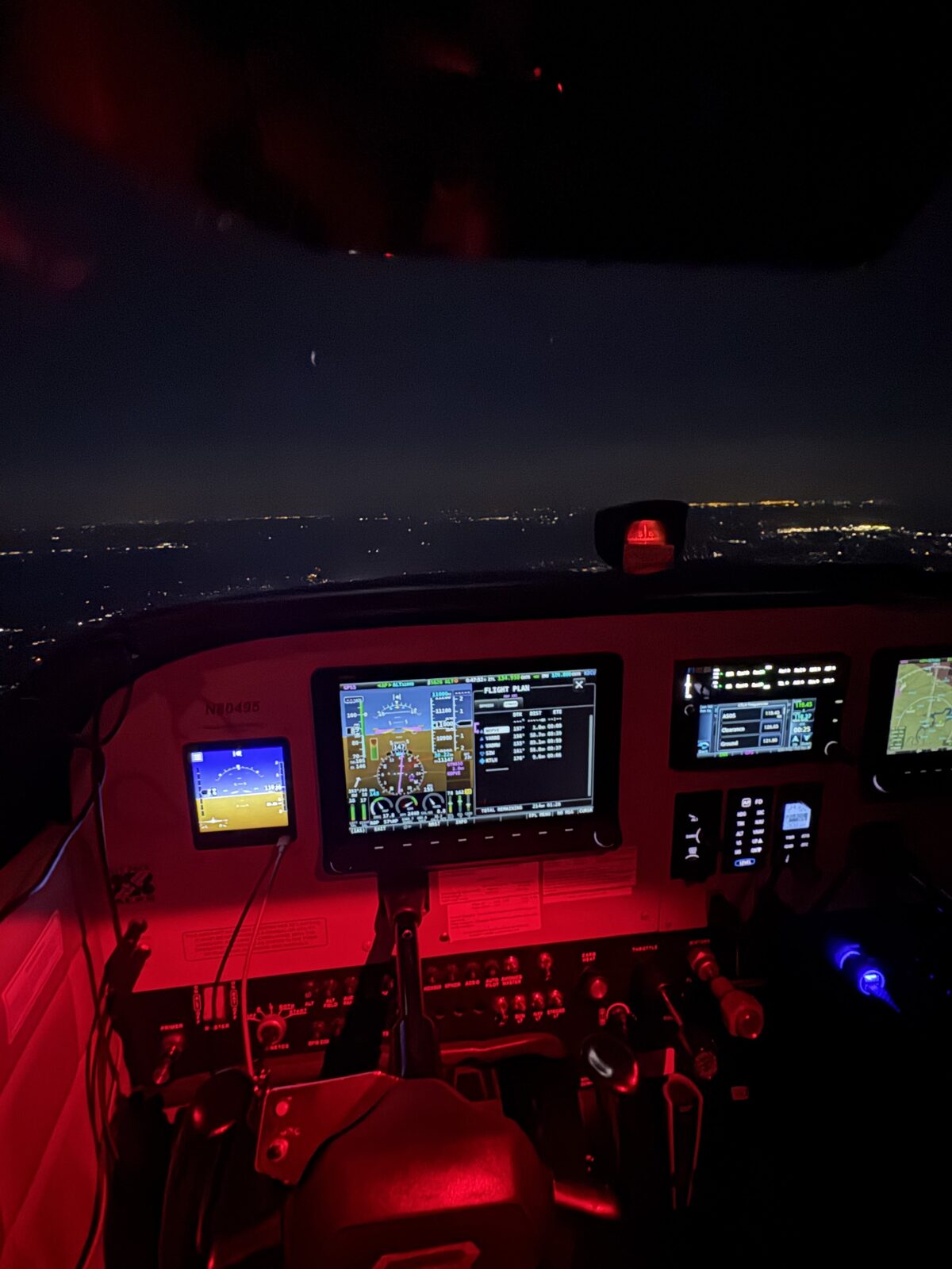 Night cockpit view of Cessna 172 N80495 with modern glass avionics over city lights